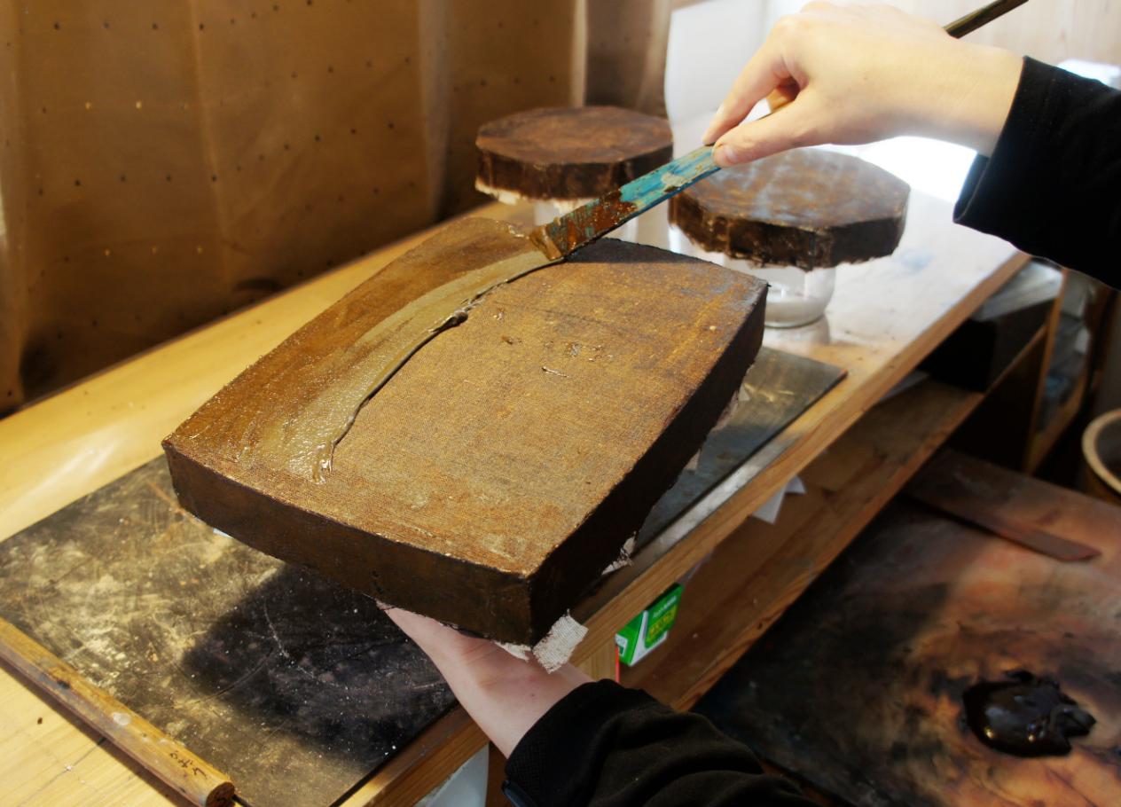 Mezuri - To fill in the concavities of the cloth, a paste mixed with Wajima ground powder, glue made of boiled glutinous rice flour and ki-urushi is applied, and the paste is scraped off the convexities with a spatula.