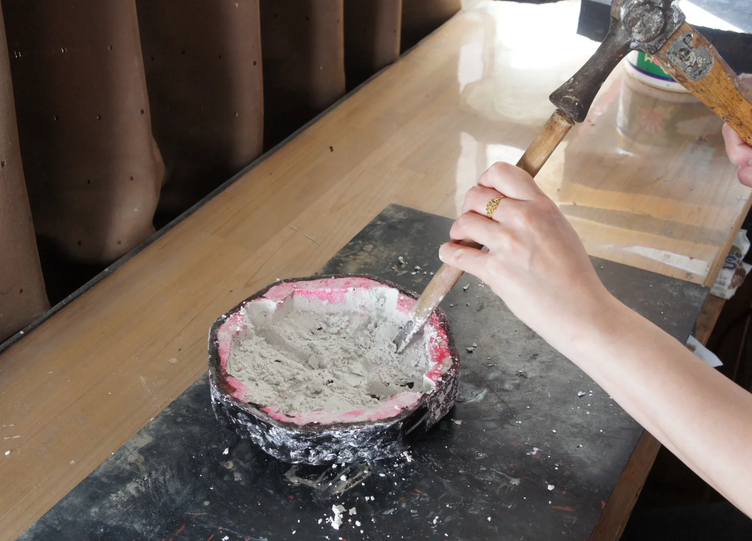 Removing the plaster mold from an octagonal box by carefully breaking it with a mallet.