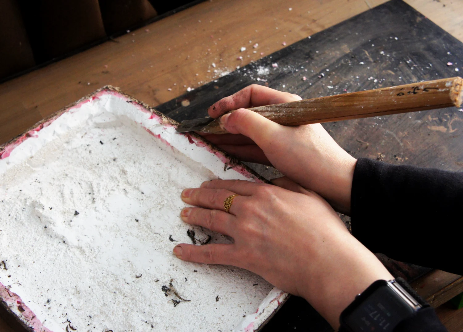 Carefully scraping away excess lacquer and hemp cloth from the edges with a carving chisel to prepare for mold removal.
