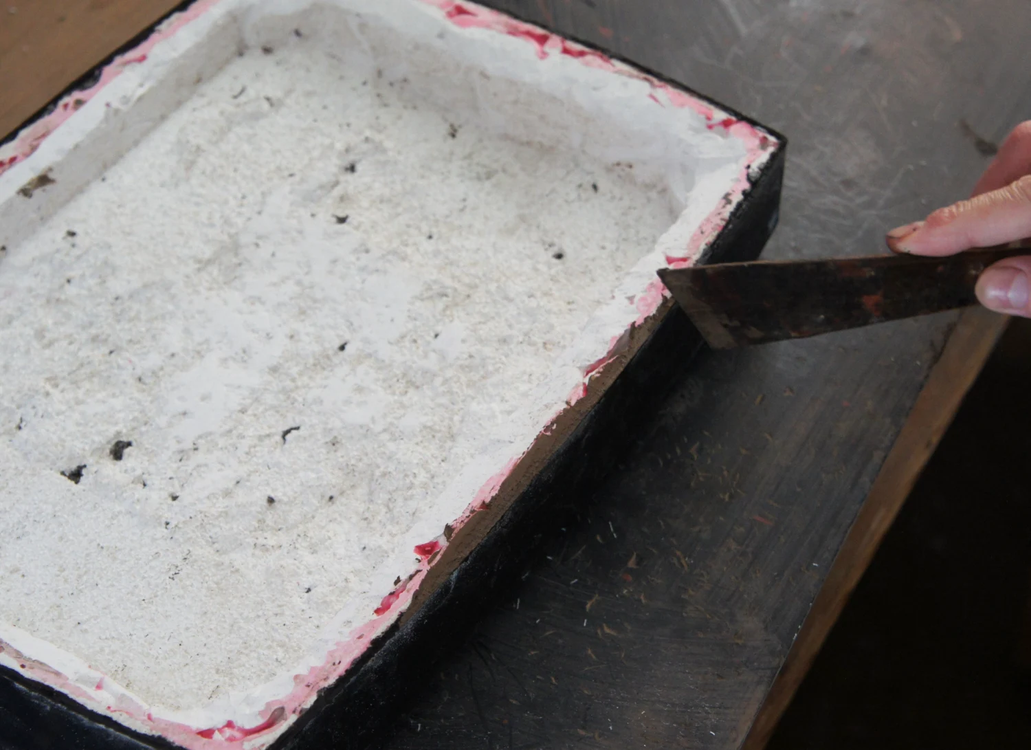 Applying Sabi (lacquer putty) to the edges to create a smooth, waterproof finish.